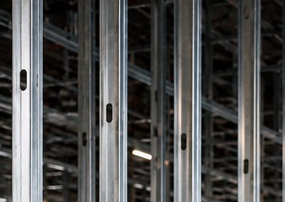 A close view of steel studs seated in floor track on a partly framed partition.